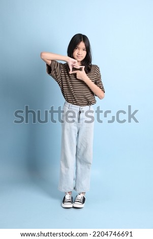 The young Asian girl with brown shirt on the blue background.