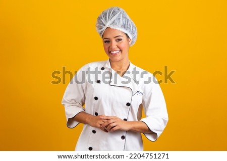 Woman chef wearing uniform and bonnet standing arms crossed and posing over isolated yellow background. occupation concept Royalty-Free Stock Photo #2204751271