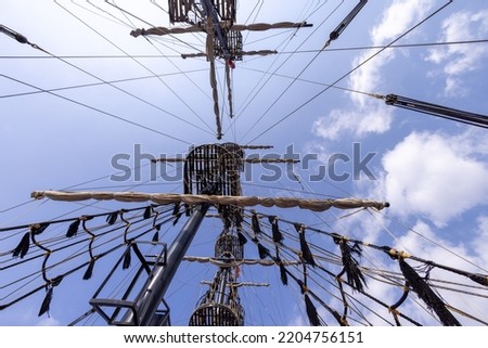 Photo looking straight up on a pirate ship showing the ships masts and ropes.