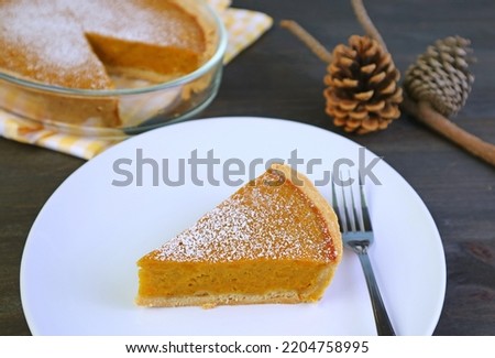 Slice of Pumpkin Pie with Blurry Pinecones for the Concept of Thanksgiving and Autumn