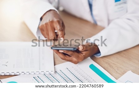 Phone, communication and doctor typing an email on a medical report while busy working with health care papers. Professional African healthcare worker texting a person the results or clinic documents Royalty-Free Stock Photo #2204760589