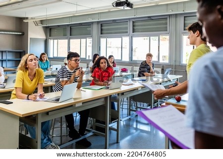 Young group of diverse high school students giving a presentation to classmate friends in classroom - Male and female college student attending to classmates lecture - Diversity and education concept