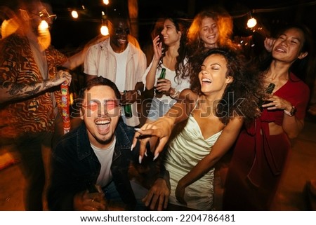 A group of multiracial people is having a blast, dancing and drinking beer at the open-air nightclub on the rooftop. Nightlife and clubbing concept. Royalty-Free Stock Photo #2204786481