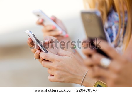Portrait of three girls chatting with their smartphones at the park  Royalty-Free Stock Photo #220478947