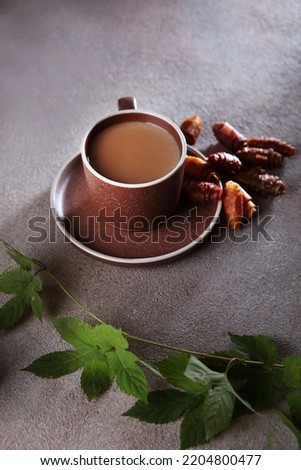 Cup of coffee and a pastille. The pastille is rolled into a roll. A branch with leaves. Healthy food without sugar.Vertical photo.