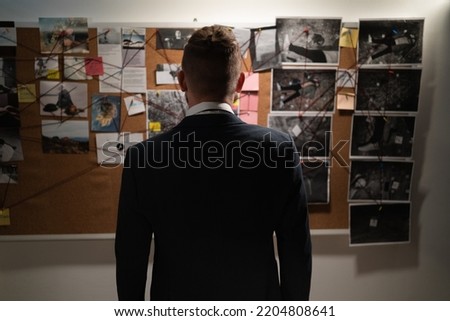 Male detective in the office near the blackboard looking for a killer working at night. view from the back without a face. copy space.