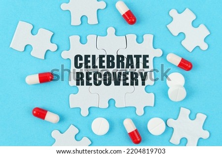 Medical concept. On a blue background, pills, capsules and puzzles with the inscription - Celebrate Recovery