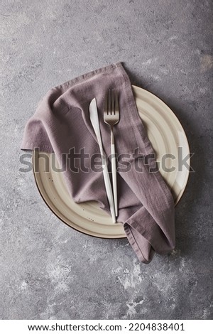 Empty gray plate with napkin and cutlery on gray background