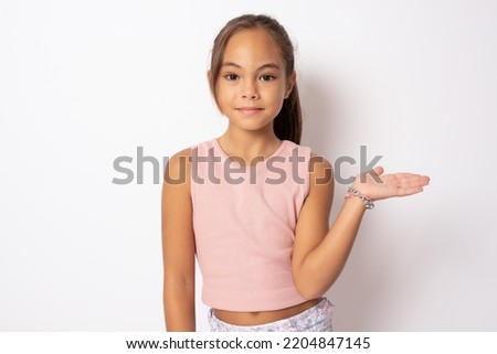 Close up of little girl holding something standing isolated over white background.