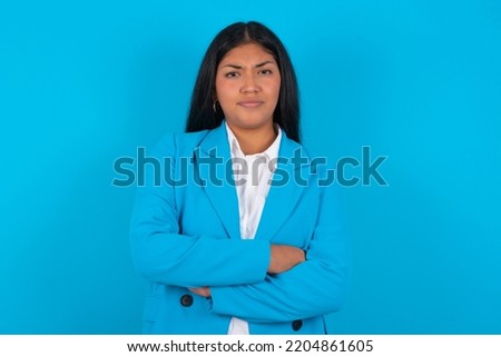 Young latin woman wearing blue blazer over blue background Pointing down with fingers showing advertisement, surprised face and open mouth