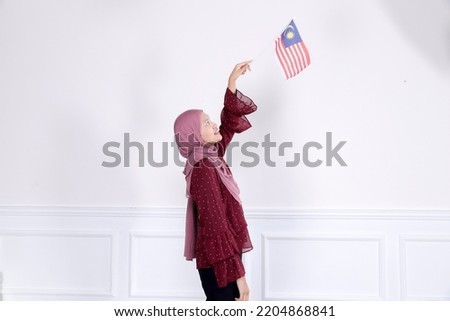 Asian women wearing hijab holding small Malaysia flag for independents day.