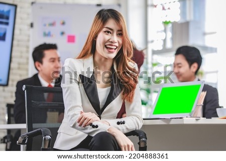 Portrait shot Asian young happy cheerful confident millennial professional successful female businesswoman in formal suit sitting crossed arms smiling while colleagues working in blurred background.
