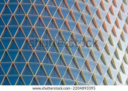 Colorful triangle pattern of the building's facade, with the sun shining on the glass