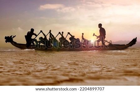 Silhouette of a Dragon boat with people paddling at sunset  Royalty-Free Stock Photo #2204899707