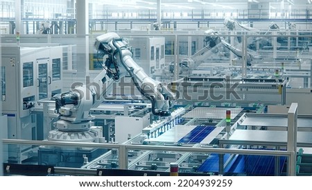 White Industrial Robot Arm at Production Line at Modern Bright Factory. Solar Panels are being Assembled on Conveyor. Automated Manufacturing Facility Royalty-Free Stock Photo #2204939259