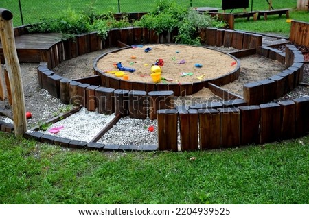 seating and a tactile walkway where you can walk barefoot. in the middle is a sandpit. a children playground made up of wooden palisades and a suspended wooden carillon Royalty-Free Stock Photo #2204939525