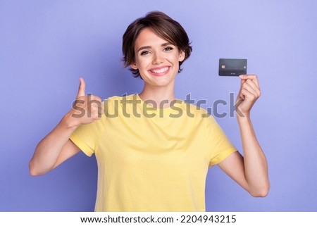 Portrait photo of young adorable gorgeous nice woman wear yellow t-shirt showing like thumb up toothy recommend bank isolated on violet color background