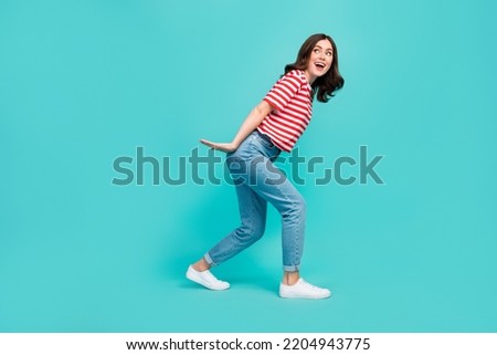 Full length photo of crazy pretty lady arm hold big size ad carry look empty space striped stylish wear isolated on cyan color background