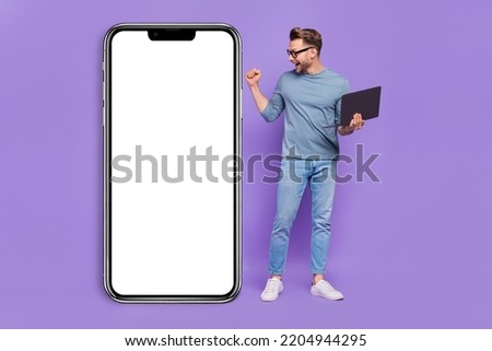 Photo of lucky excited guy dressed grey shirt rising fist typing modern gadget empty space isolated purple color background