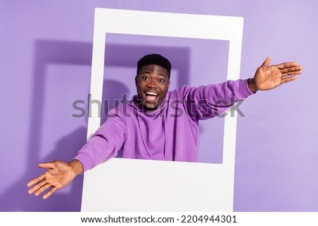 Portrait of positive funky person raise arms through paper album card isolated on violet color background