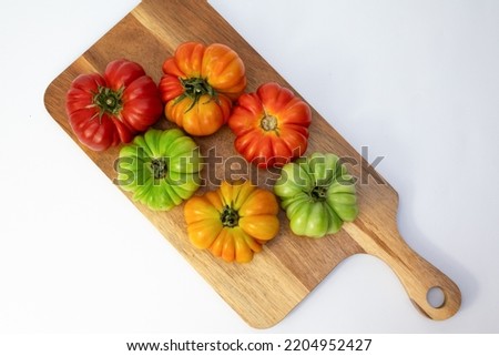 Colorful tomatoes Raf Coeur De Boeuf on white background. Raw fresh tomatos with on rustic wood texture background. Side view with soft focus. Buffalo heart tomato on white wooden rustical table.
