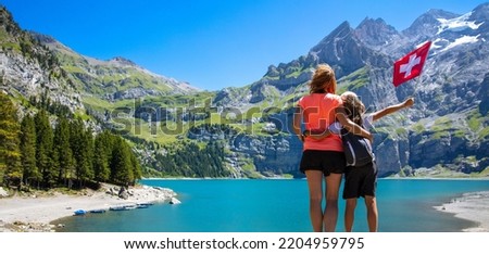 family travelling in Switzerland- mother and son with swiss flag at oeschinensee (Kandersteg) Royalty-Free Stock Photo #2204959795
