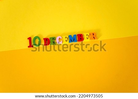 December 10 on a yellow and paper background with wooden and multicolored letters with space for text. Human rights day concept.