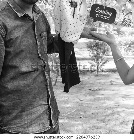 Indian couple posing for maternity baby shoot. The couple is posing in a lawn with green grass and the woman is falunting her baby bump in Lodhi Garden in New Delhi, India - Black and White