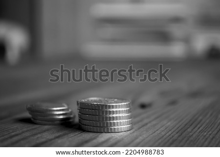 Iron money is stacked on the table. On a wooden table are two stacks of coins. Black and white photo of coins on the side.