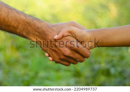 Concept of shaking hand. Friendly making a deal with a handshake of Two hands on background of Vegetables plants in Farm. Hand shaking concept. Friendship concept. Asian girl and boy shaking hands.