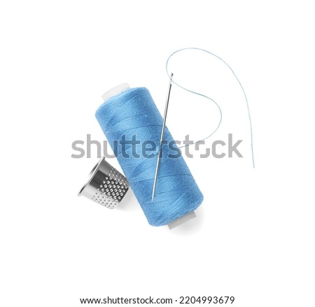 Spool of light blue sewing thread with needle and thimble on white background, top view Royalty-Free Stock Photo #2204993679