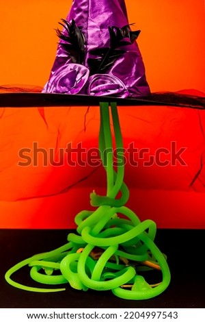 Purple witch hat with light green snakes Halloween horrors orange background