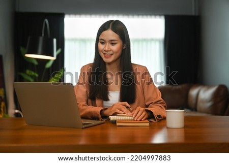 Pleased young businesswoman working, reading online Information on laptop computer