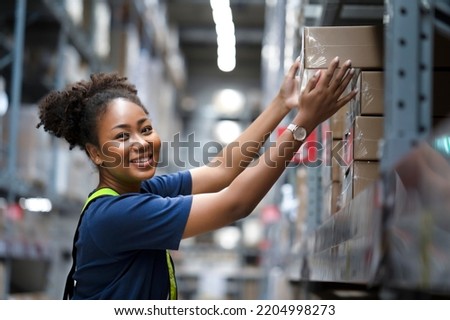African American warehouse worker take flat box from shelf in big warehouse factory, Online shopping store for logistic service to deliver the shipment, check barcode before passing to transportation Royalty-Free Stock Photo #2204998273