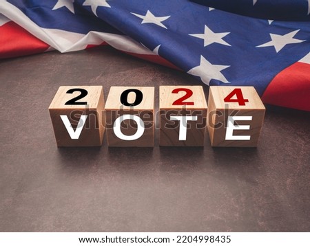 United States presidential election in 2024. Wooden cubes with text VOTE and 2024 over the American flag background. Politics and voting conceptual Royalty-Free Stock Photo #2204998435