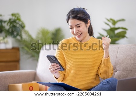Business Asian women sit on sofa use laptop computer checking customer order online shipping box at home. Starting Small business entrepreneur SME freelance. Online business, Work at home SME concept.