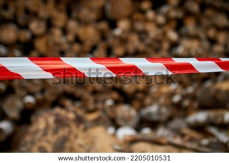 Red and white barrier warning tape, sign area for safety, Dry chopped, sawn wooden logs wooden pole texture