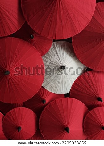 White and Red paper chinese umbrellas background. One white umbrella in group of red  umbrellas in low light.