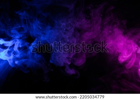 Clouds of colorful swirling blue and pink smoke dark abstract background