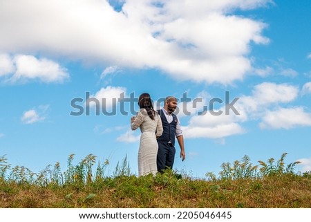 beautiful girl in a white dress and a guy in a field against a blue sky with clouds close-up