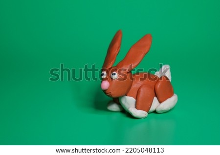 A rabbit made of plasticine on a green background.