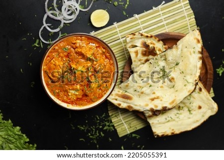 Paneer Butter Masala served with naan bread,onion rings and lemon, on a black background with space for text , Indian Curry Royalty-Free Stock Photo #2205055391