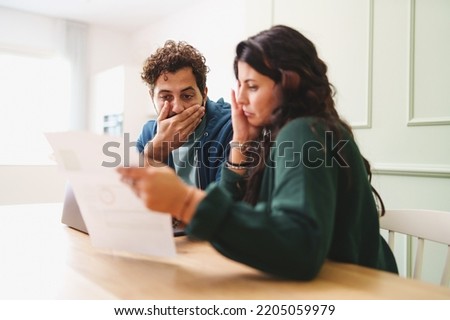 A young married couple is worried looking at the electricity bill or the arrival of very expensive taxes - lifestyle concept on the contemporary family cost of living Royalty-Free Stock Photo #2205059979