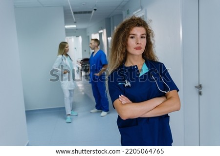 The portrait of a nurse in a blue surgical suit with her arms crossed on her chest. A professional doctor inside the hospital.