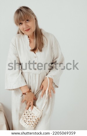 Beautiful elderly woman in a light clothes on a white background with place for text. Portrait senior woman. Elderly lifestyle at home concept.