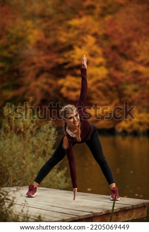 A young beautiful woman is doing exercises in the autumn forest