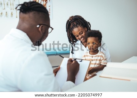 Smiling caring male pediatrician talk consult small boy patient at consultation in hospital with mother. Happy doctor do checkup examine little child at visit to clinic with mom. Healthcare concept.