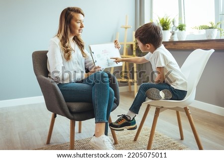 Boy listening to psychologist at meeting, thinking about her problems. A professional child education therapist having a meeting with a kid in a family support center. 