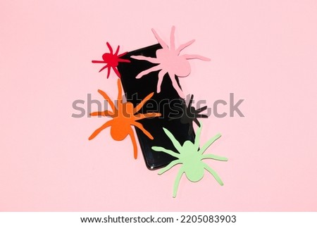 mobile phone with colorful paper spiders, creative halloween concept, pink wallpaper, paper craft