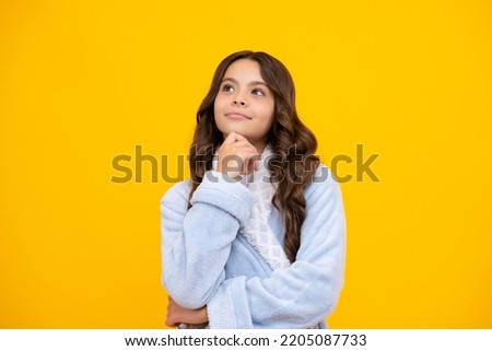 Thoughtful teenage child girl on yellow background. Portrait of a kid thinking over idea. Pensive girl.
